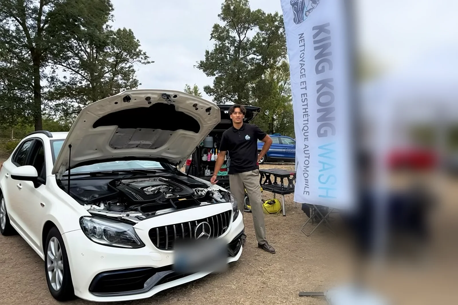 Rémy, fondateur de King Kong Wash, sur son stand à Amboise à côté d’une Mercedes capot ouvert, moteur nettoyé